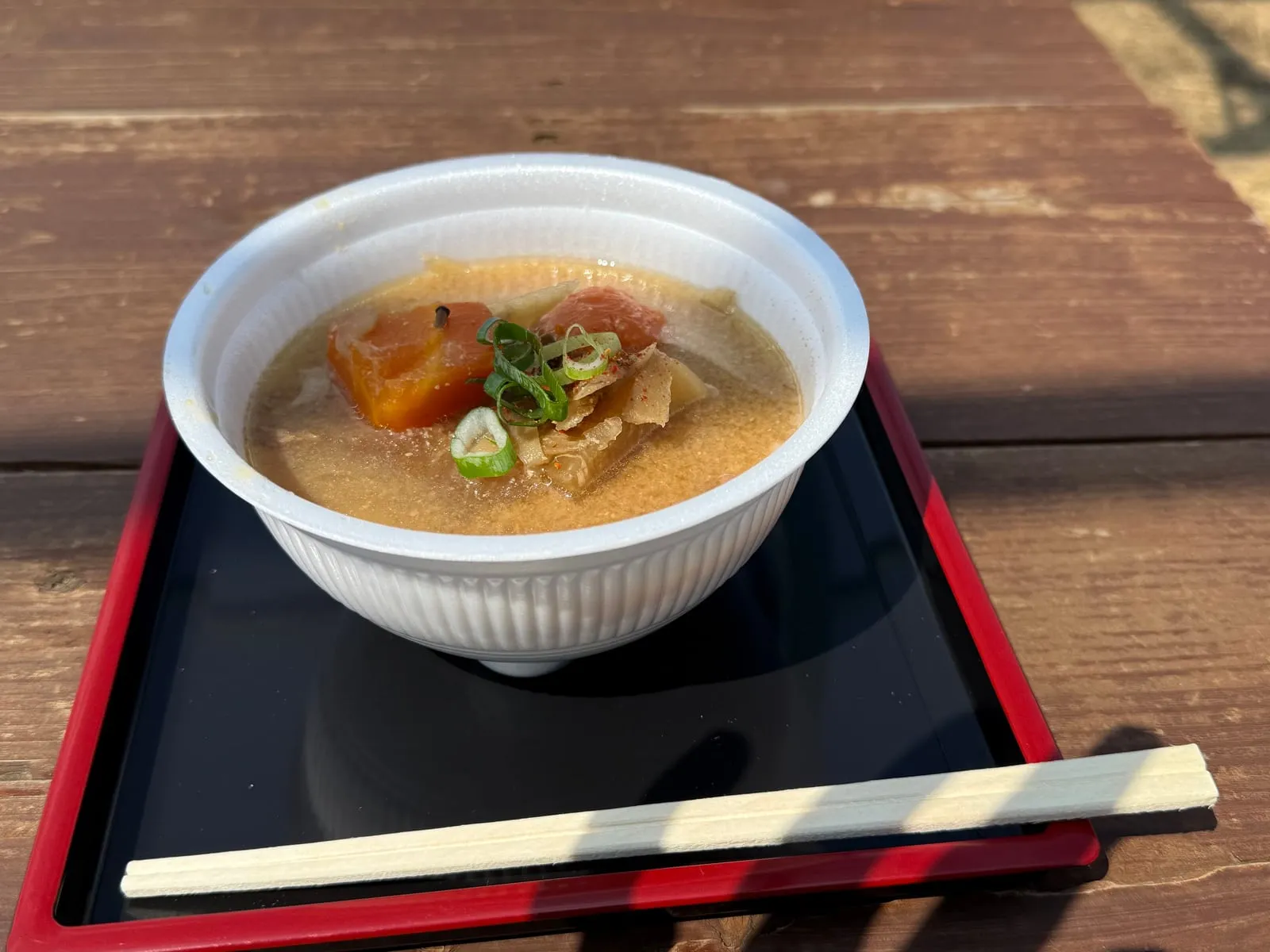 A bowl of kenchin-jiru vegetable soup on a red tray at a summit teahouse