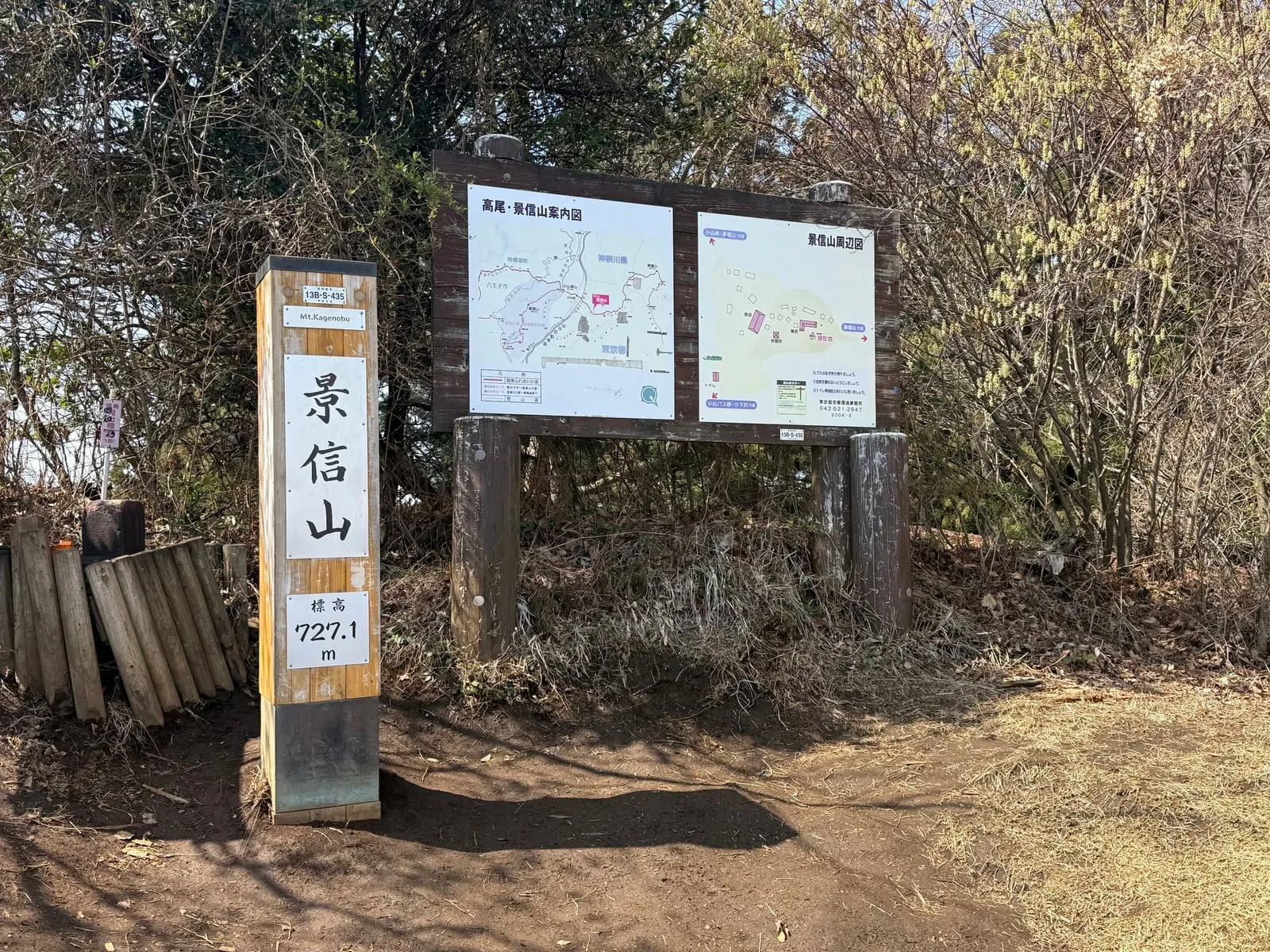 The summit marker of Mt. Kagenobu, 727.1 m, next to a trail map board